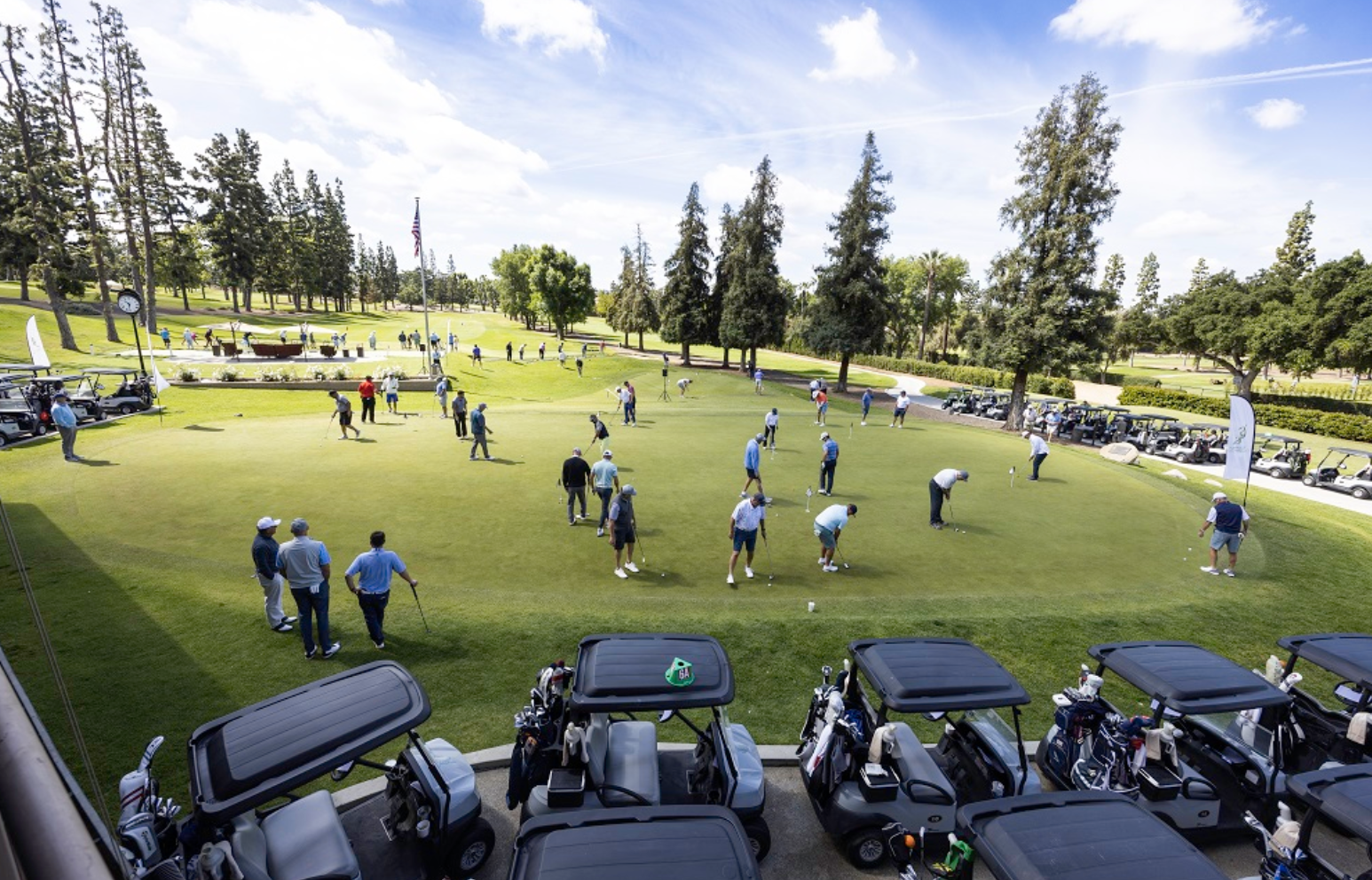 Golfers on the putting green at Glendora Country Club, with carts lined up in the foreground